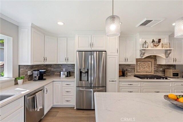 kitchen featuring white cabinetry, light stone counters, decorative light fixtures, and appliances with stainless steel finishes