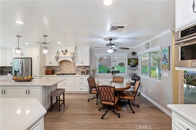 dining room with crown molding, ceiling fan, and light hardwood / wood-style flooring