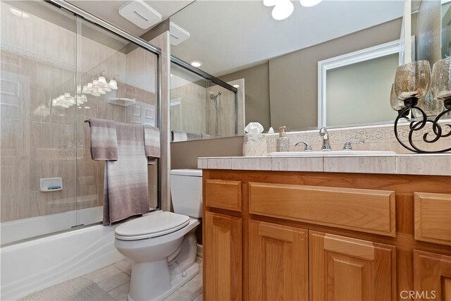 full bathroom featuring vanity, tile patterned floors, shower / bath combination with glass door, and toilet