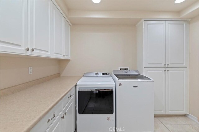 clothes washing area featuring cabinets, independent washer and dryer, and light tile patterned floors