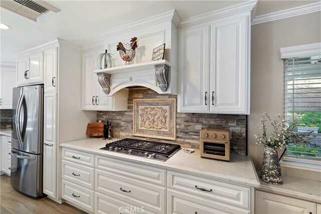 kitchen featuring white cabinetry, appliances with stainless steel finishes, light stone countertops, and backsplash