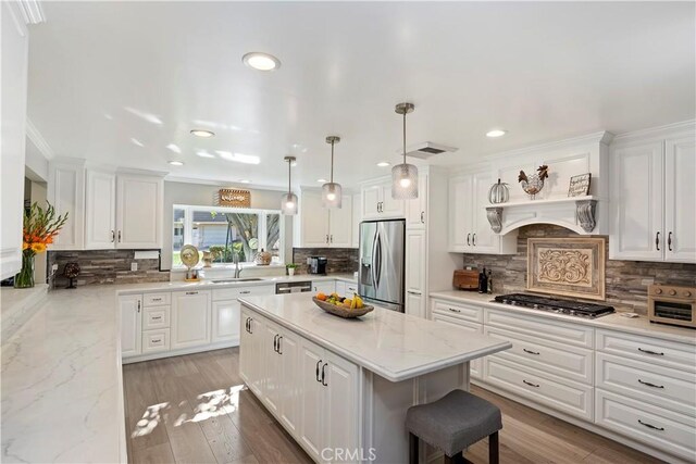 kitchen featuring light stone counters, stainless steel appliances, a center island, and white cabinets