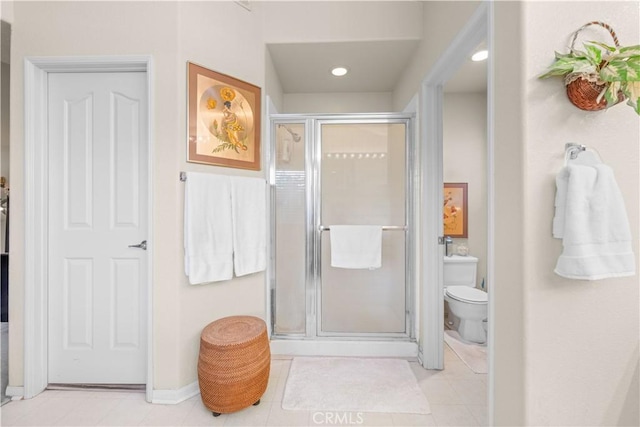 bathroom featuring toilet, an enclosed shower, and tile patterned flooring