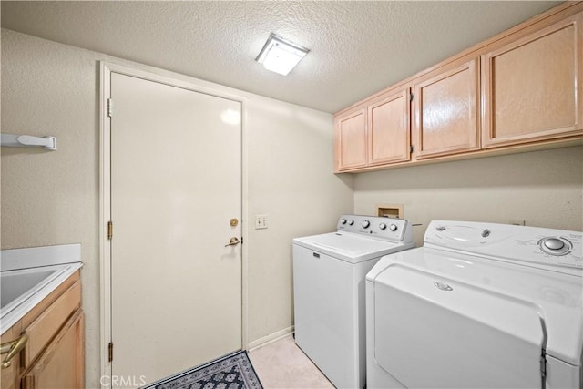 clothes washing area with cabinets, sink, washing machine and clothes dryer, and a textured ceiling