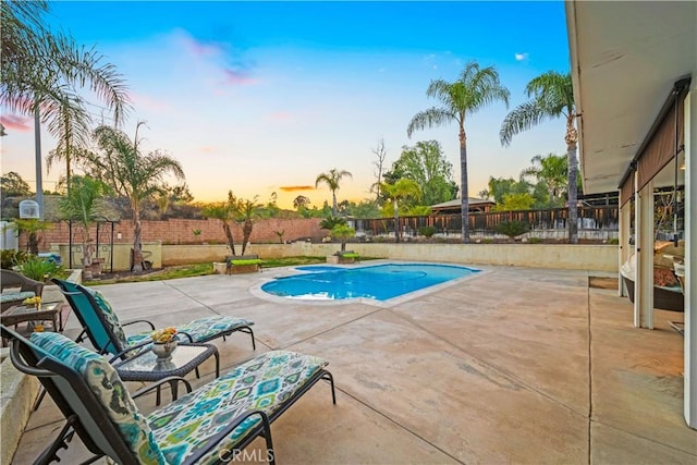 pool at dusk with a patio area