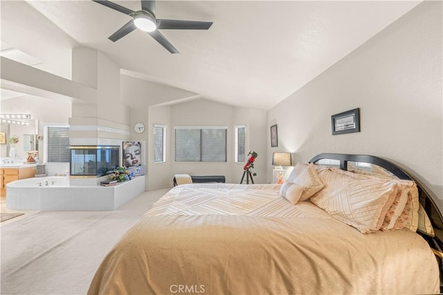 carpeted bedroom with vaulted ceiling, a tile fireplace, ceiling fan, and ensuite bathroom