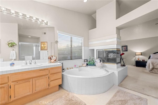 bathroom with tile patterned floors, vanity, separate shower and tub, and a tile fireplace