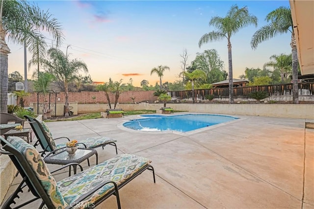 pool at dusk featuring a patio area