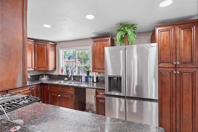 kitchen with stainless steel fridge, dark stone counters, a sink, and recessed lighting