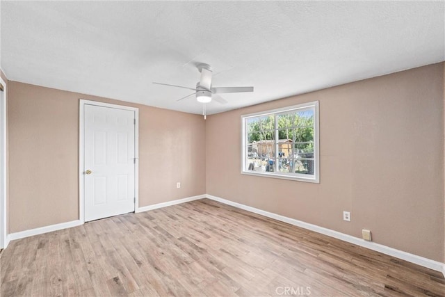 empty room featuring baseboards, ceiling fan, and light wood finished floors