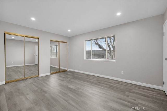 unfurnished bedroom with multiple closets and light hardwood / wood-style floors