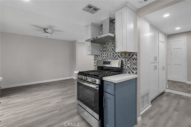 kitchen featuring white cabinets, gas stove, light hardwood / wood-style flooring, and wall chimney range hood