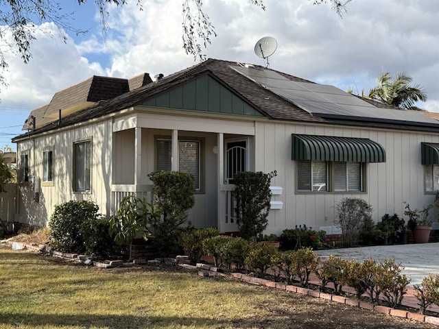 bungalow-style house featuring a front yard and solar panels