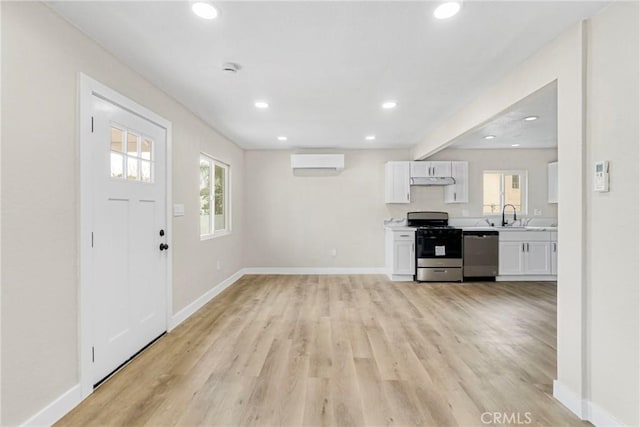 interior space featuring a healthy amount of sunlight, a wall mounted air conditioner, sink, and light hardwood / wood-style floors