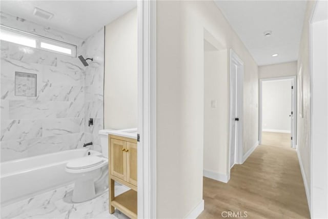 full bathroom featuring tiled shower / bath, vanity, and toilet