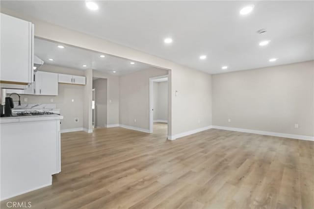 unfurnished living room with sink and light wood-type flooring