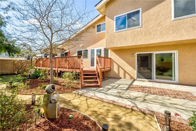 rear view of property with a wooden deck and a patio