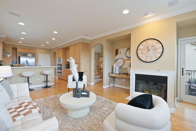 living room with crown molding and light hardwood / wood-style floors