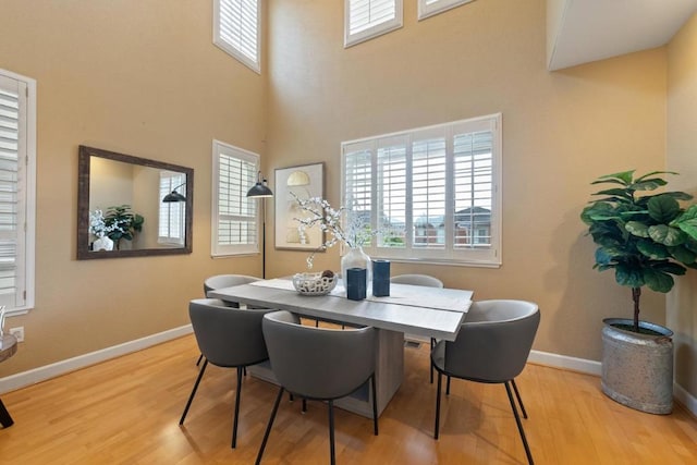 dining space featuring light hardwood / wood-style flooring and a high ceiling