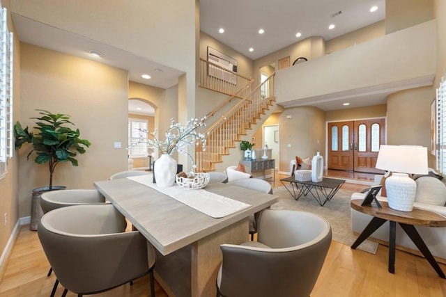 dining space with plenty of natural light, light hardwood / wood-style flooring, and a high ceiling