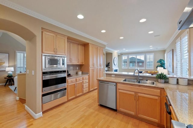 kitchen featuring appliances with stainless steel finishes, light brown cabinetry, sink, ornamental molding, and light hardwood / wood-style floors