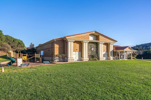 rear view of property with a playground and a lawn