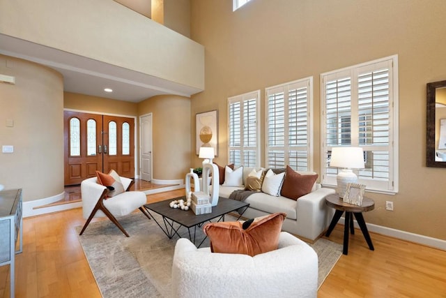 living room featuring a towering ceiling and light hardwood / wood-style floors