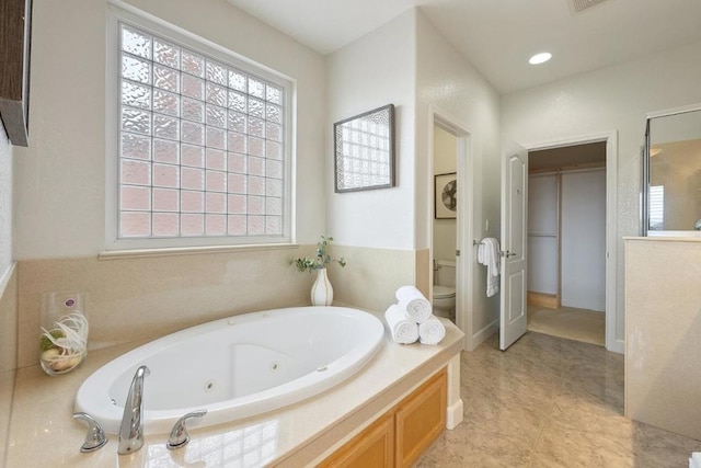 bathroom with tile patterned floors, toilet, and tiled bath