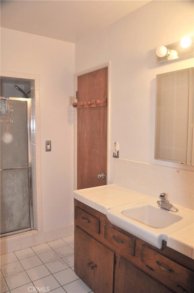 bathroom featuring tile patterned flooring, vanity, tasteful backsplash, and walk in shower