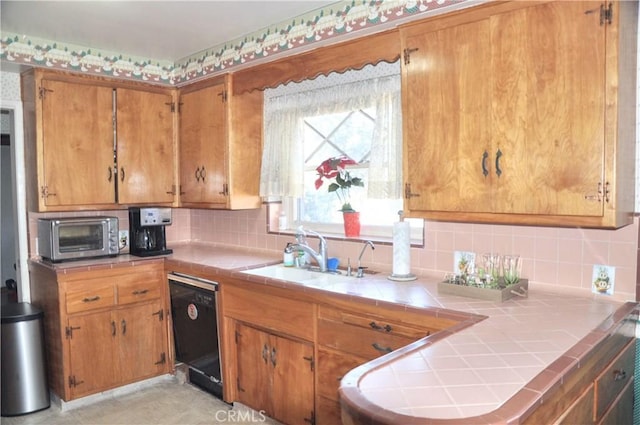 kitchen with tasteful backsplash, sink, tile countertops, and dishwasher