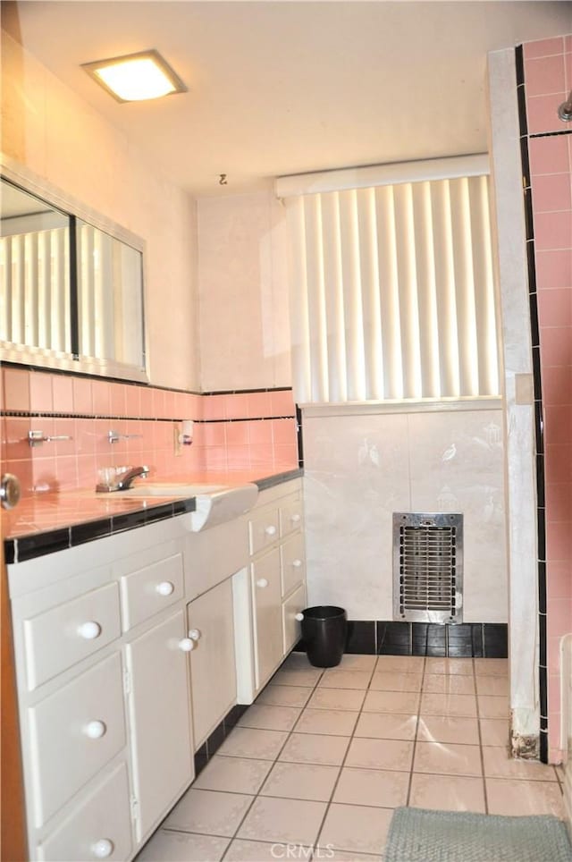 bathroom with tile patterned flooring, vanity, heating unit, and tile walls