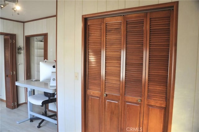 unfurnished office with ornamental molding, light hardwood / wood-style floors, and wood walls