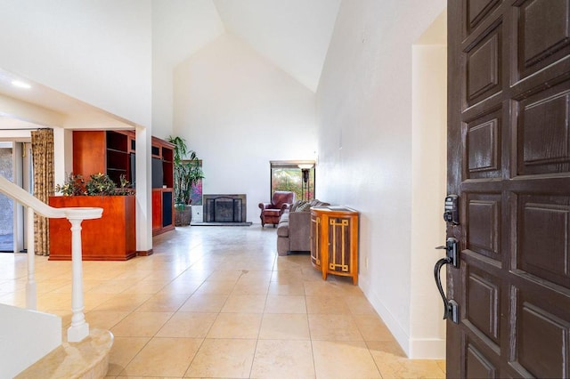 foyer featuring light tile patterned floors and high vaulted ceiling