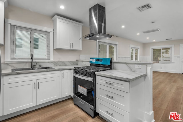 kitchen featuring sink, white cabinets, island exhaust hood, kitchen peninsula, and stainless steel gas range oven