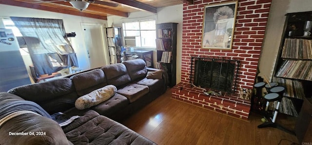 living room with hardwood / wood-style floors, a fireplace, beamed ceiling, ceiling fan, and wooden ceiling