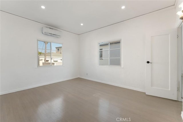 unfurnished room with hardwood / wood-style flooring and an AC wall unit