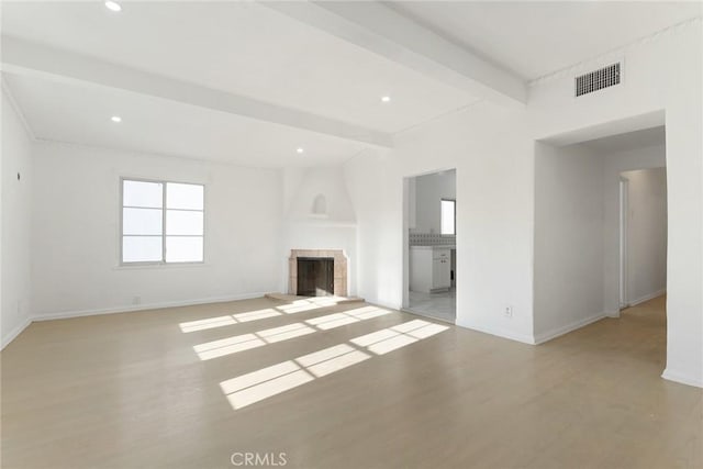 unfurnished living room with beam ceiling and light wood-type flooring