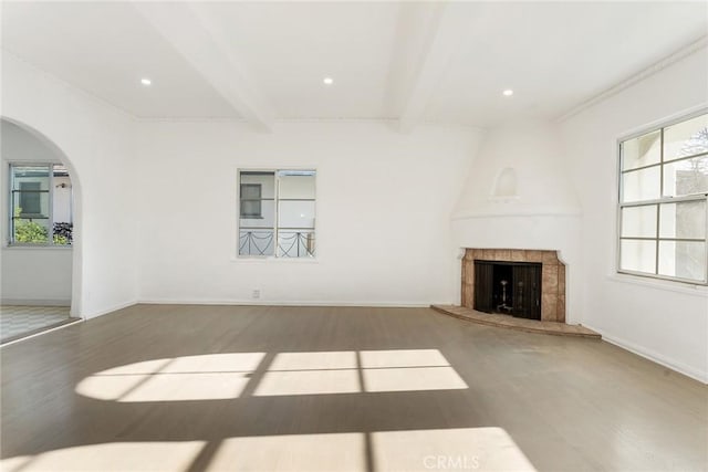 unfurnished living room featuring a fireplace, wood-type flooring, and beam ceiling