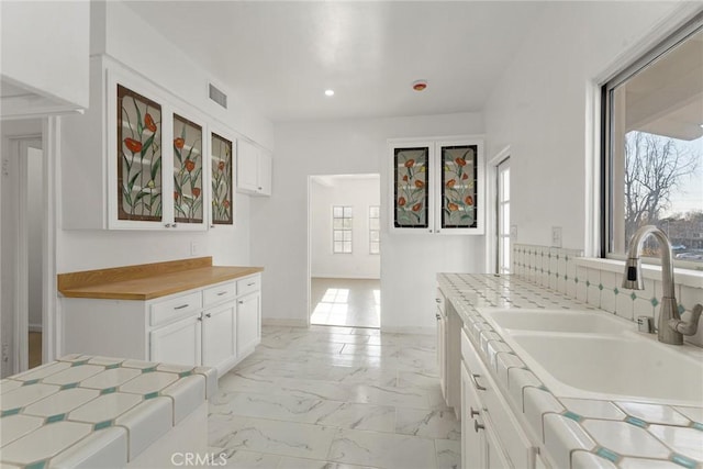 kitchen featuring a healthy amount of sunlight, sink, and white cabinets