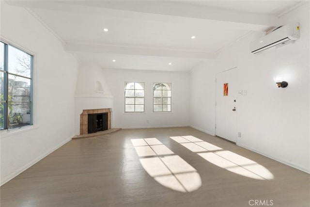 unfurnished living room featuring a fireplace, beam ceiling, light hardwood / wood-style flooring, and an AC wall unit