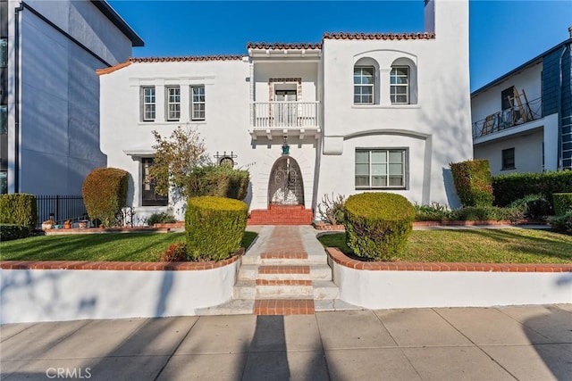 mediterranean / spanish house with a balcony and a front lawn