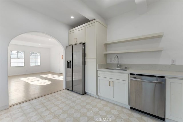 kitchen with white cabinetry, sink, stainless steel appliances, and beamed ceiling