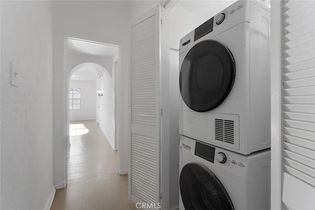 laundry room with stacked washer / dryer and light hardwood / wood-style flooring