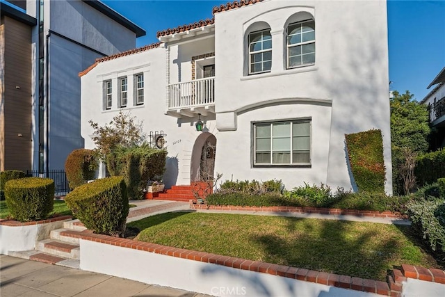 mediterranean / spanish house with a balcony and a front yard