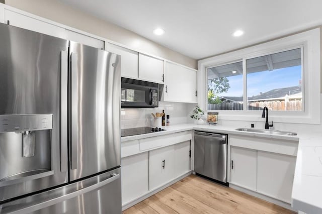 kitchen with backsplash, white cabinets, sink, and black appliances