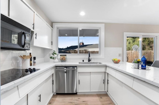 kitchen featuring white cabinetry, sink, light stone counters, and black appliances