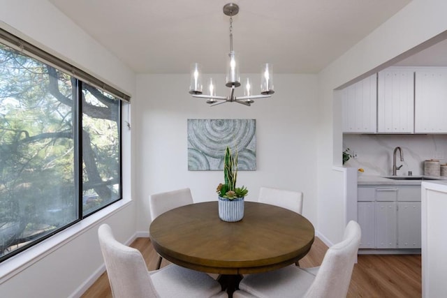 dining space with hardwood / wood-style flooring, sink, and a notable chandelier