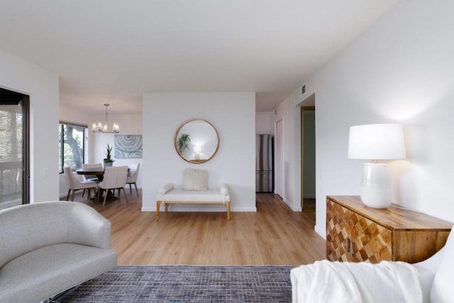 living room with an inviting chandelier and light wood-type flooring