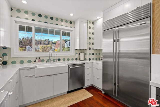 kitchen featuring dark wood-type flooring, sink, tasteful backsplash, appliances with stainless steel finishes, and white cabinets