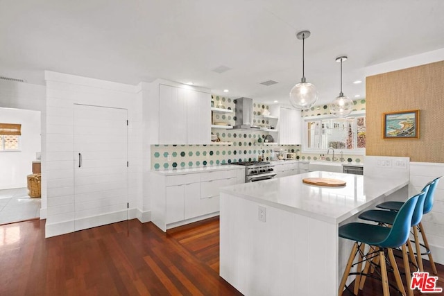 kitchen with decorative light fixtures, white cabinetry, a kitchen breakfast bar, stainless steel range, and kitchen peninsula